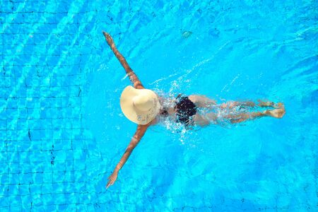 view from above. Slender girl in a hat swims. Vacation on the water.の写真素材
