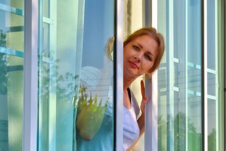 Beautiful girl looks out of the open window. Advertising new Windows.