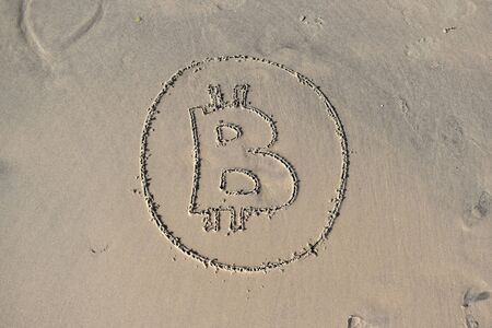 Symbol of bitcoin on the sand. Sign cryptocurrencies. Drawn bitcoin on the beach.の写真素材
