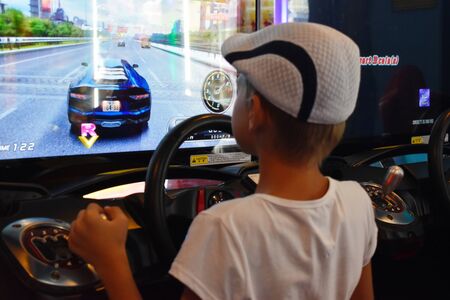 Thailand. Hua hin. January 2020. A boy plays computer games at the Mall. simulator machine games. Car racing game with the wheel.のeditorial素材