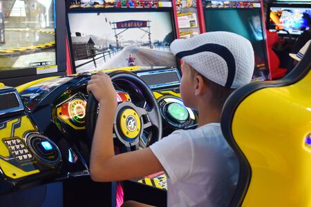 Thailand. Hua hin. January 2020. A boy plays computer games at the Mall. simulator machine games. Car racing game with the wheel.のeditorial素材