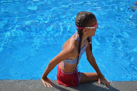 Child girl dives into the pool. Girl learning to swim autdoor.の写真素材