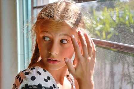 Cute child girl peeking. Beautiful girl peeping. The Sly glance of the child. The child spies. Hide-and-seek.の写真素材