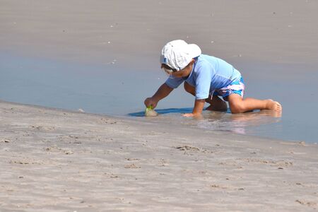 A small child plays in the sand on the beach for the day.のeditorial素材