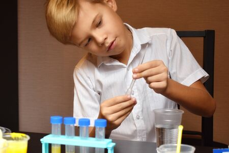 Student boy tinkering with test tubes. The child does experiments at home. Children's home lab