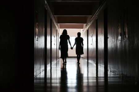 Silhouette of two girls in a dark room.の写真素材