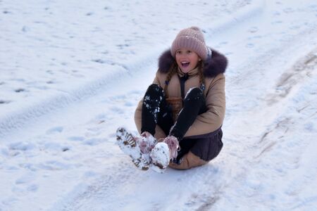 Child girl kid winter fun in the snow. The girl is lying on the ice. Enjoy the winter and snow.の写真素材