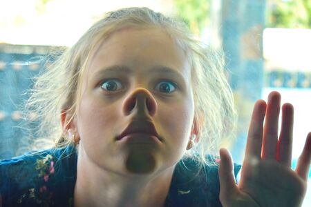 The girl sees into the window. A funny baby. Girl fooling around.