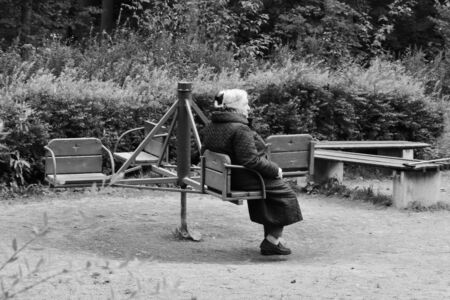 Monochrome photo. Loneliness and poverty in old age. Old grandmother on a childrenの写真素材
