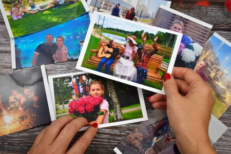Female hand holding a photograph. Setting family photos. Watch family photo album.の写真素材