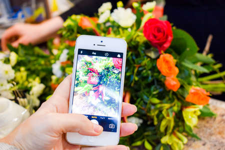 Florist at work photographing the bouquet. Taking pictures of flowers on your smartphone