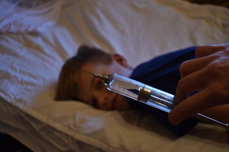 The boy and a large syringe. Medical vaccination. Anti-vaccine children