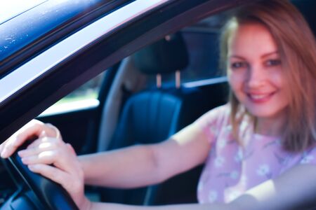 Beautiful girl sitting in a black car. Pleasure from driving a car.の写真素材