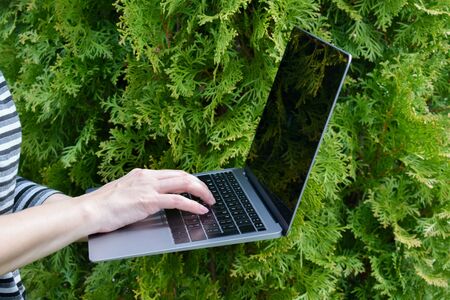 the laptop is in the green garden. Woman working on computer.の写真素材