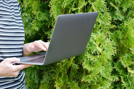 the laptop is in the green garden. Woman working on computer.の写真素材