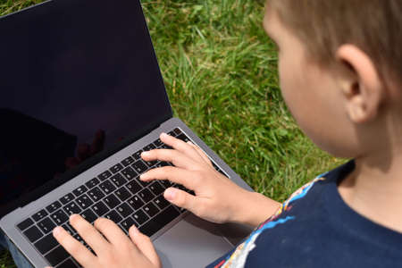 Boy child learning online outdoor. Family education at home. Distance learning on laptop.の写真素材