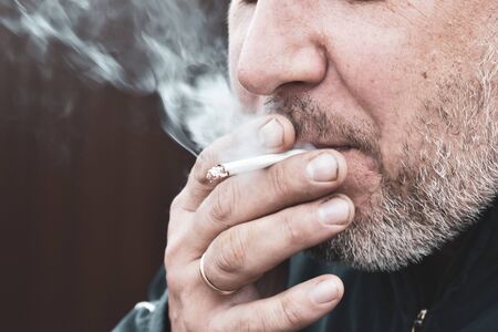 the harmfulness of cigarette Smoking. smelly tobacco smoke. A man smokes