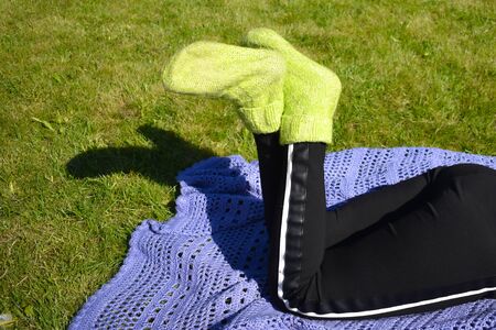 Lying on green grass in knitted socks in summer. Relax in garden in morning.の写真素材