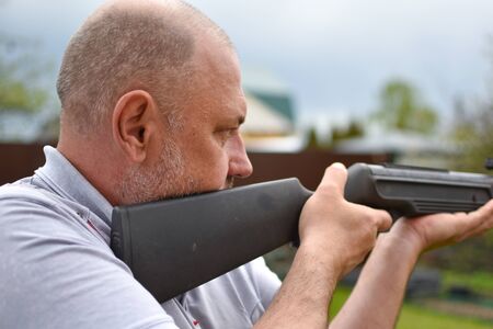 aged man with a rifle in the garden shoots at hobby targetsの写真素材