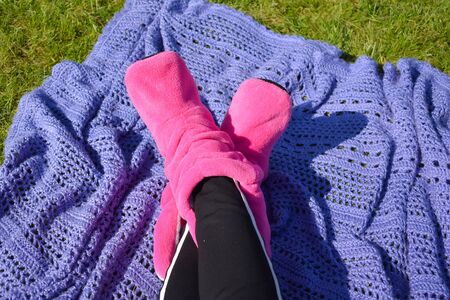 Lying on green grass in knitted socks in summer. Relax in garden in morning.