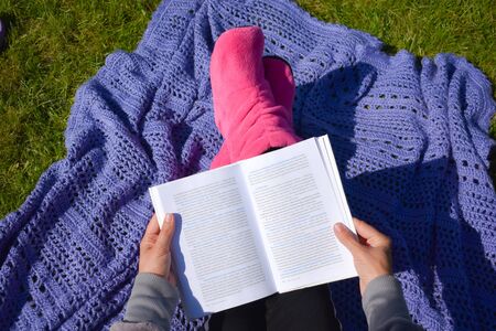 Girl reading a book on the grass. Distance learning outdoor