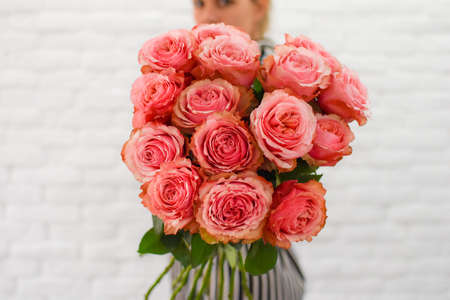 a young girl with pleasure holds in her hands pink peonies bouquet.の写真素材