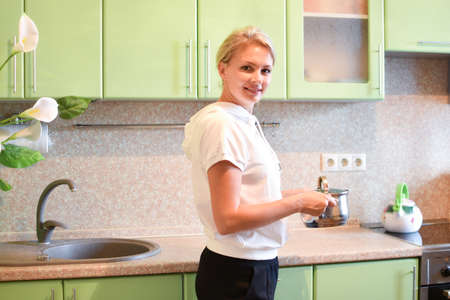 woman cooks in cozy kitchen at home. housewife prepares dinner in saucepanの写真素材