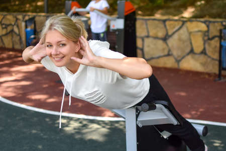 Happy sportswoman on gym outdoor. Woman on a sports trainer on sports ground. Sports for health.