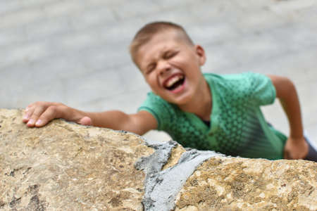 boy teenager climbs a stone mountain. dangerous extreme games of children outside. climbing training