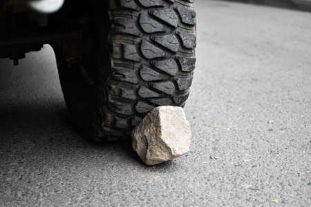 stone under the wheel of car. wheel chock. parking on mountain. danger of rolling off vehicleの写真素材