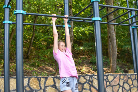 Caucasian teenager girl on gym outdoor playground. children's sports for health. a girl of 10-14...