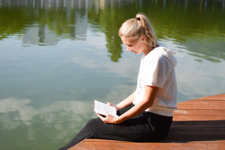 young woman resting in the summer park in nature. enjoyment and relaxation in the fresh air. pensive blonde outdoor girlの写真素材