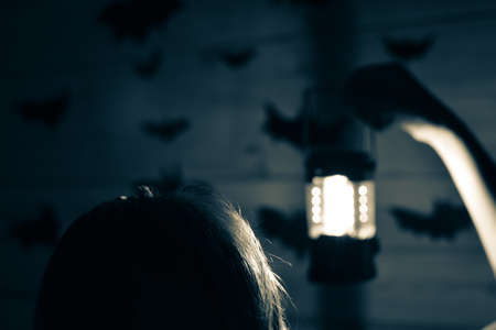 person with a lantern on background of wall with bats. scary surprise for halloween holiday....