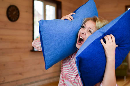 woman covered ears with pillow. Noisy neighbors make it difficult to live peacefully. woman was tired of loud neighbors and covered ears. Harmful neighbors.の写真素材