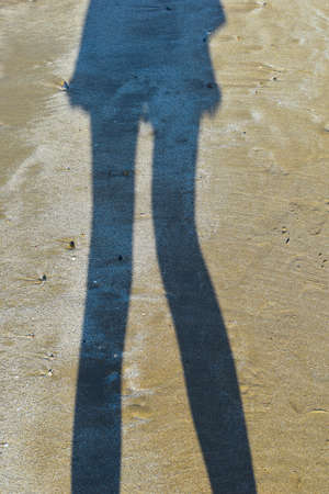 shadow from female feet on wet sand. reflection silhouette feet on beach