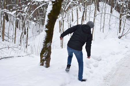 snow falls from a tree in the forest on a man. man falls on a snowy road. man will run away from an avalancheの写真素材