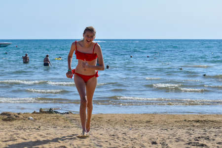 a slender beautiful girl teenager in a swimsuit runs along the seashore. fun vacation by the sea
