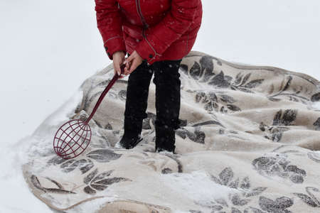 beat the carpet from dust in the winter in the snow. cleaning home carpets with snow. the carpet lies on white snowの写真素材