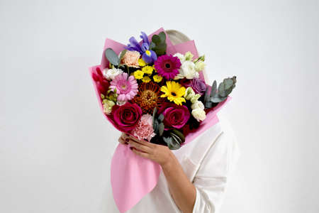 beautiful bouquet of flowers in the hands of a woman. photo for postcard and catalog of an online flower shop. fresh flower deliveryの写真素材
