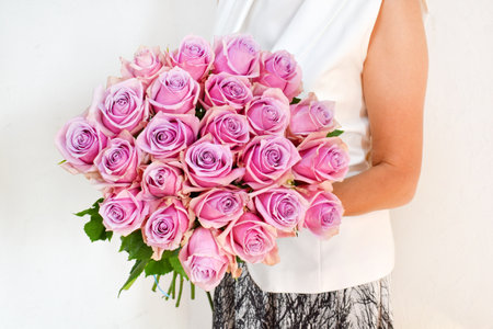 A bouquet of fresh pink roses in the hands of a woman.Beautiful fresh flowers for the holiday. Woman with flowers indoors.の写真素材