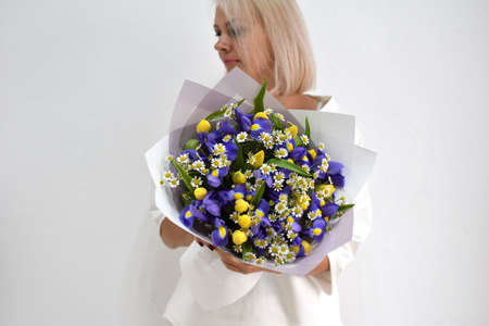 beautiful bouquet of flowers in the hands of a woman. photo for a postcard and catalog of an online flower shop. fresh flower deliveryの写真素材