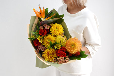 beautiful bouquet of flowers in the hands of a woman. photo for a postcard and catalog of an online flower shop. fresh flower deliveryの写真素材
