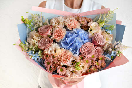 Woman with a bouquet of flowers. Beautiful flowers for the holiday. Woman with beautiful flowers in her hands indoors background. A bouquet of flowers for a flower shop.の写真素材