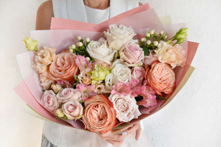 Woman with a bouquet of flowers. Beautiful flowers for the holiday. Woman with beautiful flowers in her hands indoors background. A bouquet of flowers for a flower shop.の写真素材