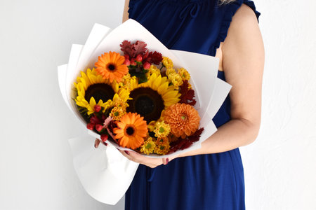 Woman with a bouquet of flowers. Beautiful flowers for the holiday. Woman with beautiful flowers in her hands indoors background. A bouquet of flowers for a flower shop.の写真素材