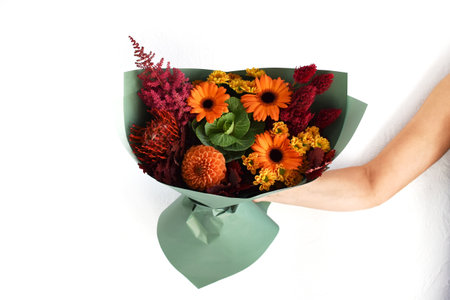 Woman with a bouquet of flowers. Beautiful flowers for the holiday. Woman with beautiful flowers in her hands indoors background. A bouquet of flowers for a flower shop.の写真素材