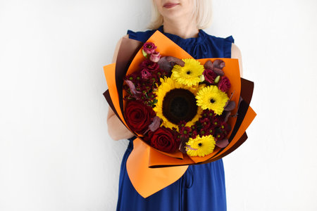 Woman with a bouquet of flowers. Beautiful flowers for the holiday. Woman with beautiful flowers in her hands indoors background. A bouquet of flowers for a flower shop.の写真素材