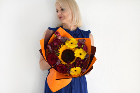 Woman with a bouquet of flowers. Beautiful flowers for the holiday. Woman with beautiful flowers in her hands indoors background. A bouquet of flowers for a flower shop.の写真素材