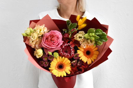 Woman with a bouquet of flowers. Beautiful flowers for the holiday. Woman with beautiful flowers in her hands indoors background. A bouquet of flowers for a flower shop.の写真素材
