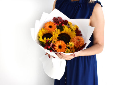Woman with a bouquet of flowers. Beautiful flowers for the holiday. Woman with beautiful flowers in her hands indoors background. A bouquet of flowers for a flower shop.の写真素材